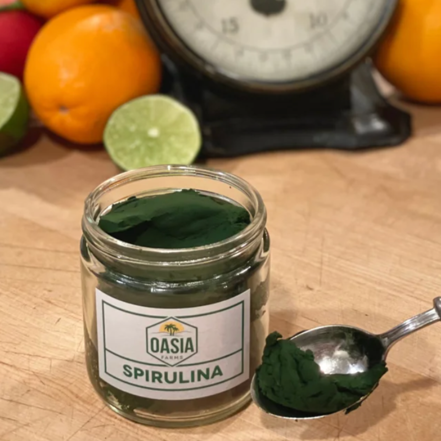 One jar of raw Oasia Farms spirulina with a spoon showing the lovely texture of raw, never frozen spirulina